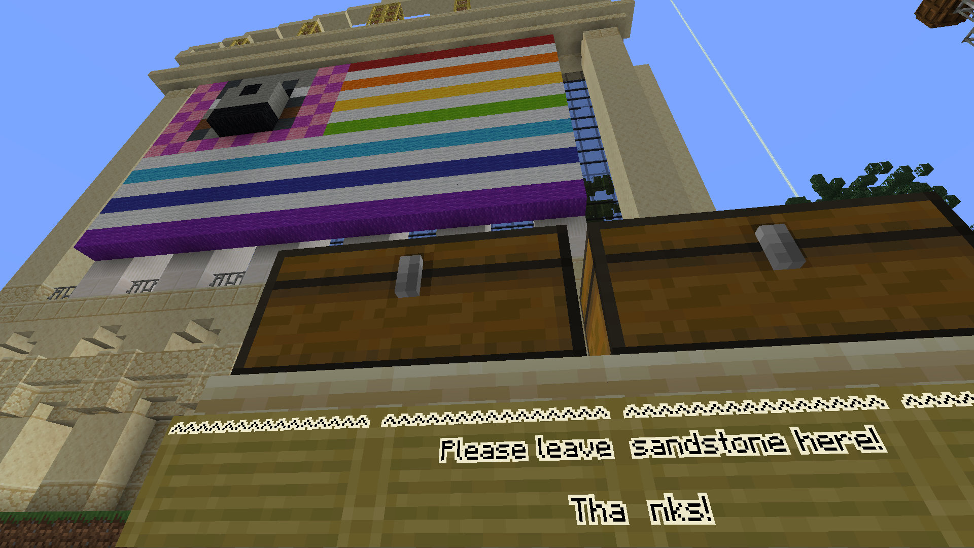 A screenshot of Minecraft showing the Wool Street from the front. It is a sandstone rendition of the New York Stock Exchange entry with a striped flag with a wolf on it.