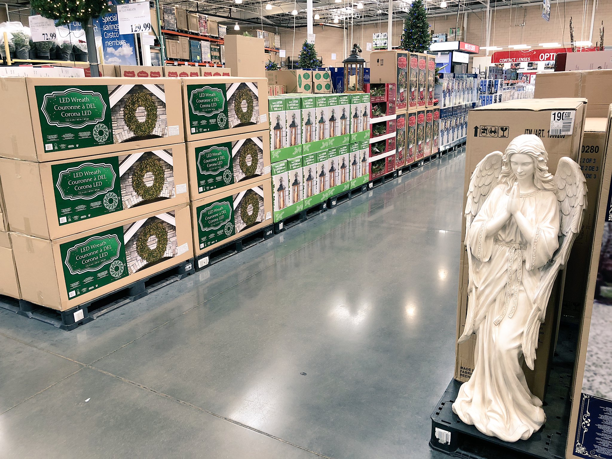 A photograph of the Nashville Charlotte Ave Costco seasonal aisle full of Christmas decorations such as trees, wreaths, and ornaments. In the foreground is a five-foot-tall statue of an angel standing on a plastic pallet.